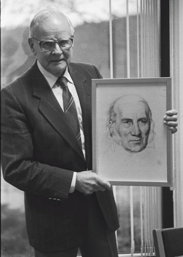 En svartvit bild på Bernhard Toftgård med porträttet av Grundtvig.