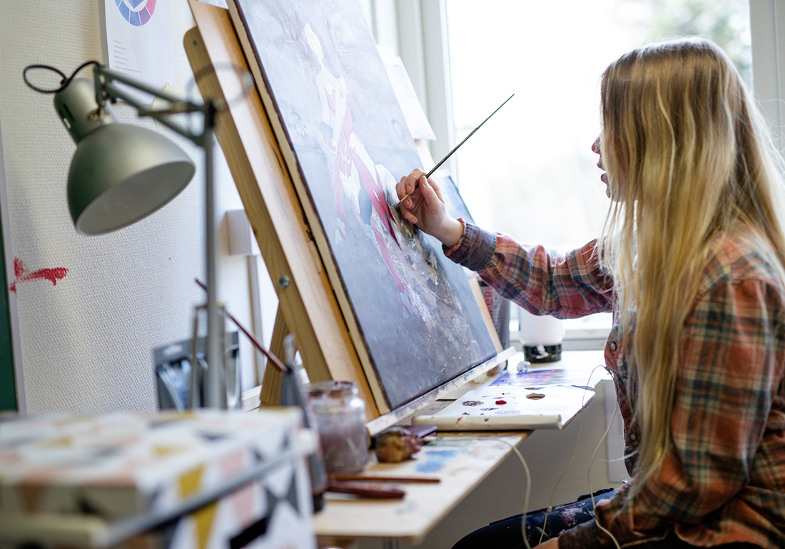 En person som sitter och målar vid sin ateljé plats